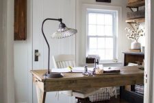 a welcoming farmhouse home office with a wooden desk, a jute rug, open shelves, a metal chandelier and a crystal lamp