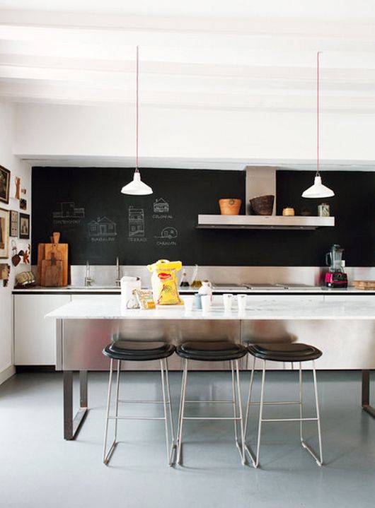 a white minimalist kitchen with a chalkboard wall plus a tiny metal backsplash is a stylish space with no excessive decor
