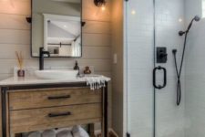 an elegant farmhouse bathroom with black and white mosaic tiles, a wooden vanity and touches of black for drama