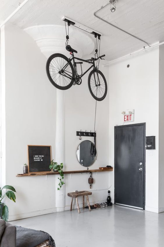 a Scandinavian space with a bike holder attached to the ceiling allows to store it in a creative and comfortable way and make it part of decor