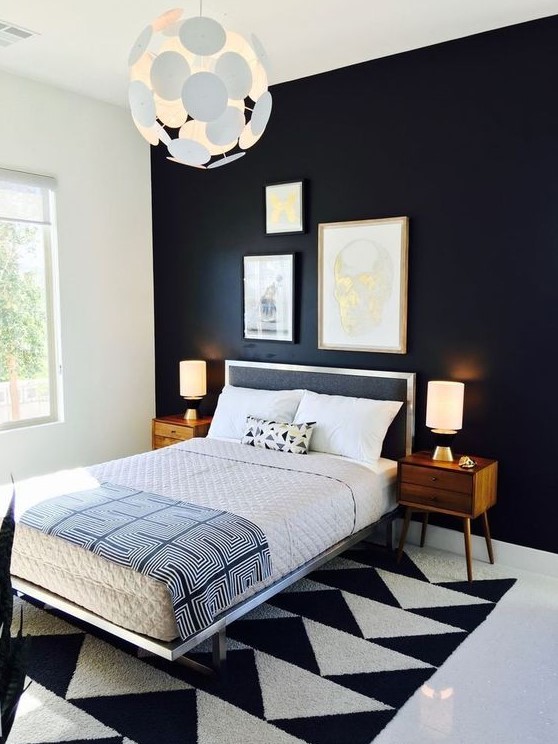 A bold and dramatic mid century modern bedroom with a black statement wall, a geometric rug, a black bed and rich stained nightstands