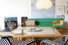 a bright and catchy living room with a bold green sofa and bright pillows, a large coffee table and striped loungers