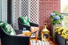 a bright and stylish balcony with layered rugs, wicker chairs and printed pillows, potted blooms and a large candle lantern