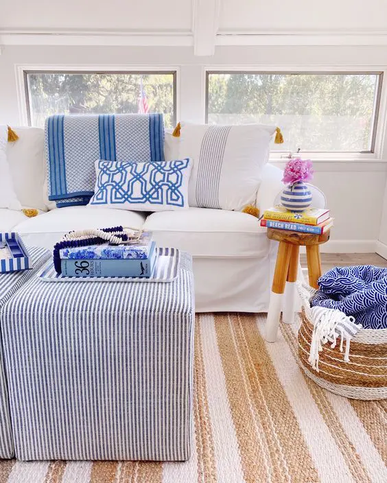 a bright modern sunroom with white and striped furniture, printed pillows and a jute rug is very cool