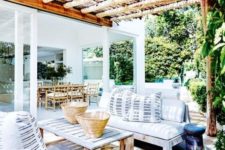 a bright summer terrace with wooden furniture, watercolor rugs and striped pillows feels very island-like