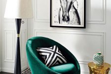 a chic living room with a printed black and white rug, a green chair with a printed pillow, a gold side table and a large floor lamp
