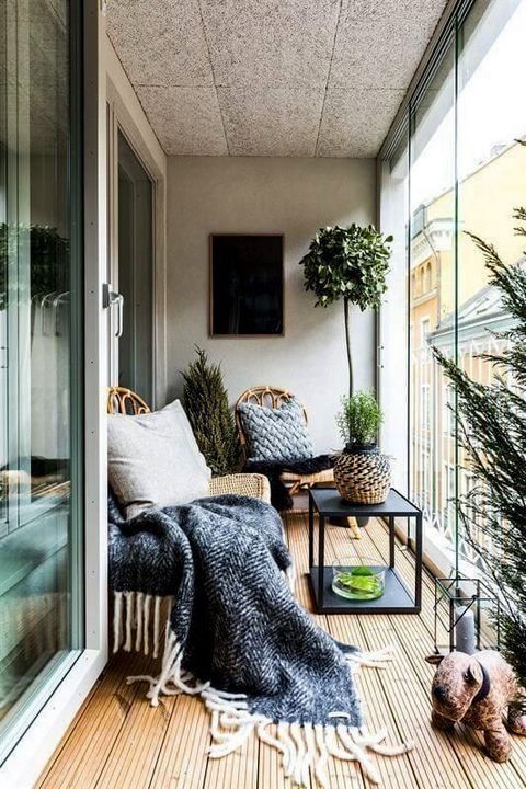 a contemporary sunroom with a boho feel - a couple of wicker loungers, a table, a lantern and potted greenery