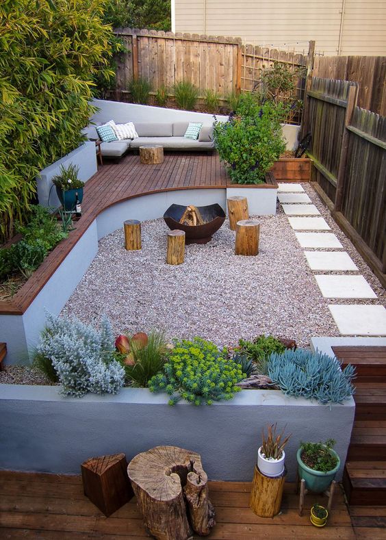 a contemporary terrace with a raised wooden deck, a gravel space with a fire pit and catchy plants