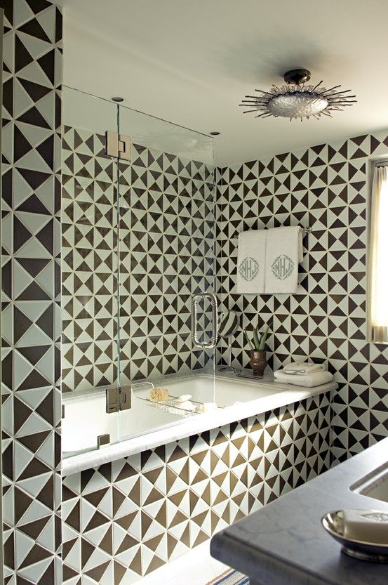 a contrasting bathroom clad with black and white geo tiles, shiny metallic fixtures and touches is veyr eye-catchy and very bold