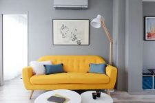a cool mid-century modern living room with grey walls, a yellow sofa, round tables, a floor lamp and a geo rug
