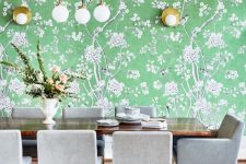 a fantastic dining space with a green floral accent wall, a stained dining table, grey and gold square chairs and a grey geo print rug