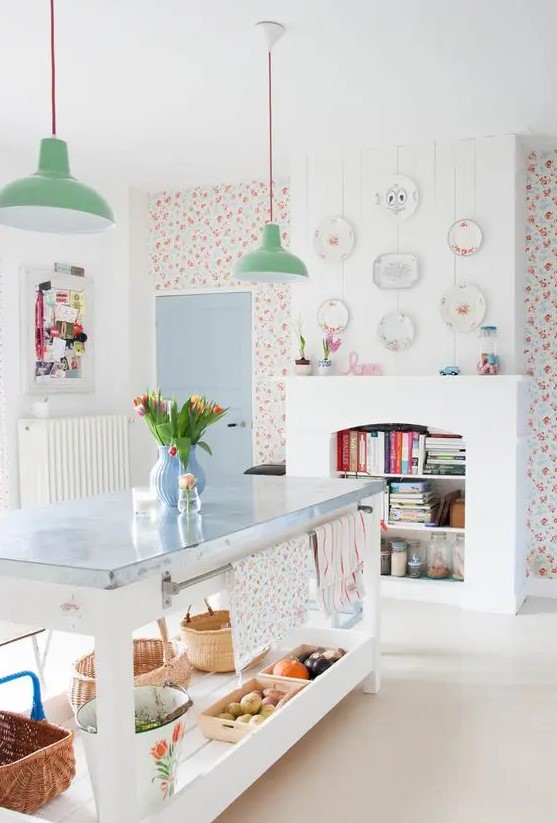a kitchen with bright floral wallpaper, a non-working fireplace with book storage, a kitchen island and green pendant lamps