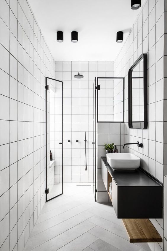a laconic black and white bathroom with square white tiles and herringbone tiles on the floor, a black floating vanity and black fixtures