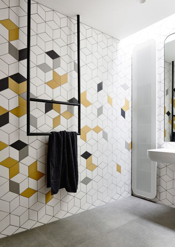 a minimalist bathroom with white, grey, mustard and geo tiles, a narrow window, black fixtures and white appliances