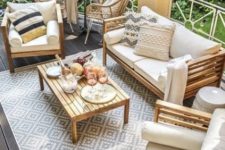 a neutral summer terrace with wooden furniture, potted plants, rattan chairs and lots of cool textiles