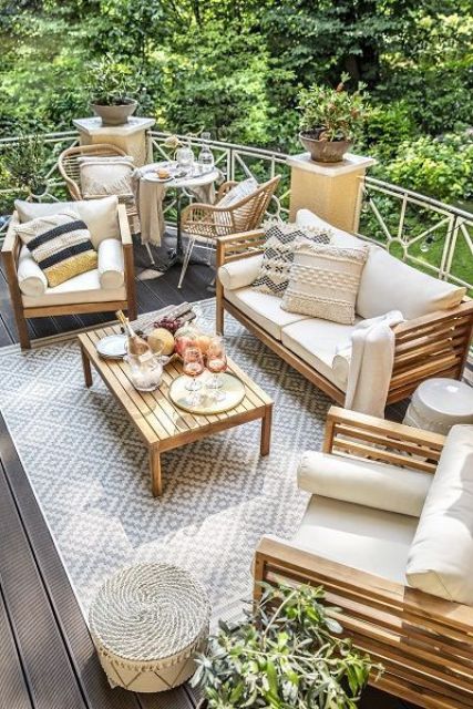 a neutral summer terrace with wooden furniture, potted plants, rattan chairs and lots of cool textiles