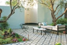 a refined modern terrace with a Mediterranean feel with greenery and succulents, a tiled deck, metal furniture and a fountain