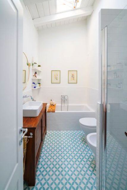 a serene bathroom with a skylight, done in white and with a blue geo tile floor plus a stained wooden vanity