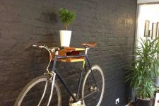a simple and colorful shelf for holding a bike, with potted greenery is a cool idea to store your bike anywhere you want
