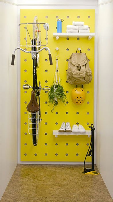 a sunny yellow pegboard with shelves, hooks and a bike holder is a lovely idea to store a lot of things and without sacrificing any floor space