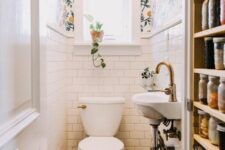 a tiny white powder room with white subway tiles, bright floral wallpaper, a wall-mounted sink and white appliances