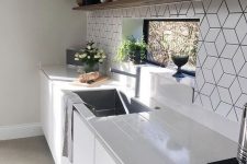 a white Scandinavian kitchen with white countertops, an open shelf for storage and a white geo tile backsplash plus potted plants