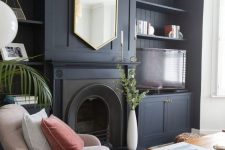 an exquisite living room with a midnight blue built-in shelving unit and cabinets, a fireplace, a hexagon-shaped mirror and a striped rug