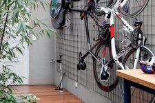 an outdoor space with a grid on the wall and bikes attached to the grid is a very cool and fresh idea to store them outdoors
