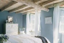 a cozy bedroom with blue walls and light wood