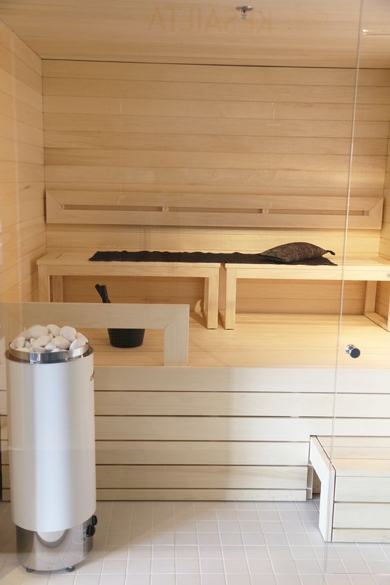 a chic whitewashed wooden sauna with several benches and just some light is welcoming
