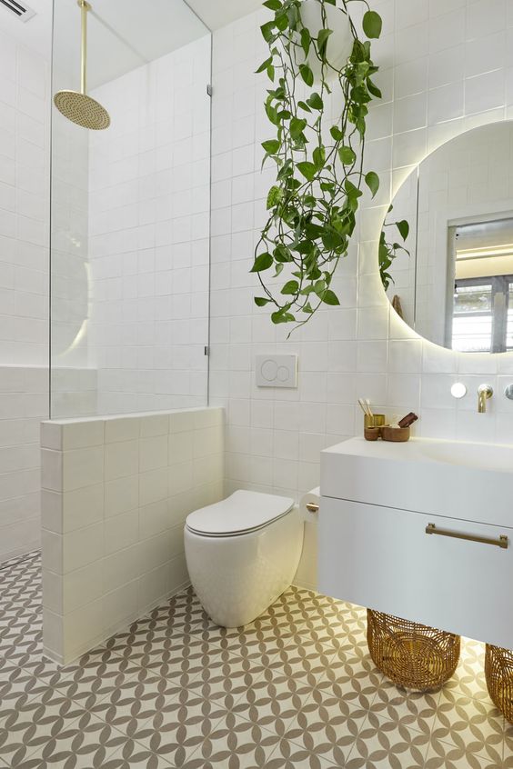 a contemporary bathroom clad with mosaic tiles, with a floating vanity, a half wall with glass to separate the shower space and a potted plant