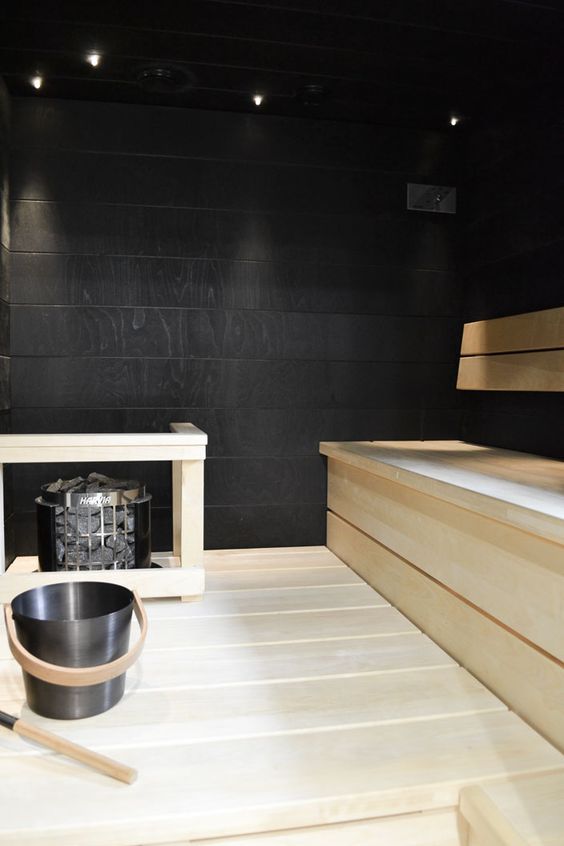 a contrasting black and white steam room with black walls and light stained wooden furniture is cool