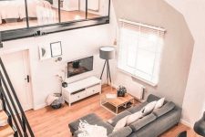 a cool modern space with a loft sleeping space, a living-dining space below, grey and white furniture, a staircase with a black metal frame