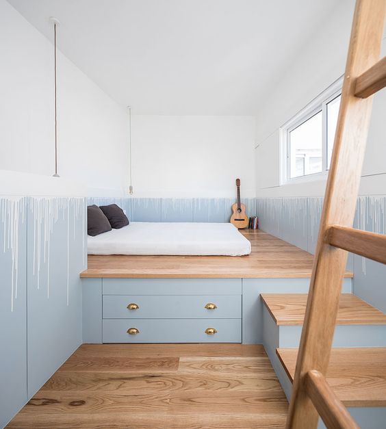 a custom-designed wooden platform with steps and drawers for storage saves much space in a tiny bedroom