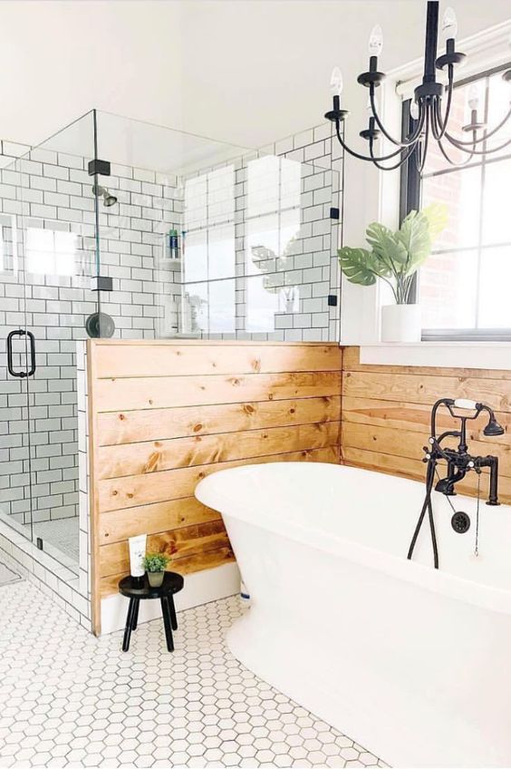 a farmhouse bathroom clad with hex and subway tiles, a pony wall clad with wood and a lovely vintage chandelier