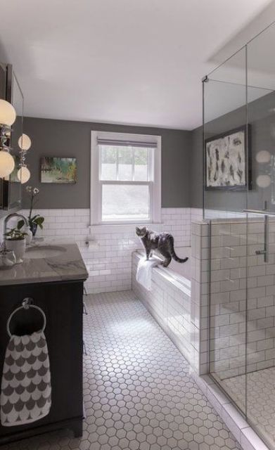 a farmhouse bathroom with white subway tiles and hex ones, with grey walls, a shower space with a pony wall and a black vanity