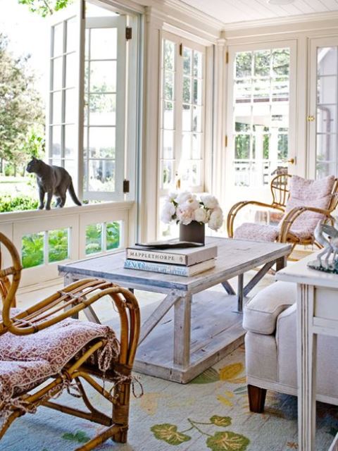 a light vintage sunroom with vintage wooden and rattan furniture, pastel and neutral textiles and blooms