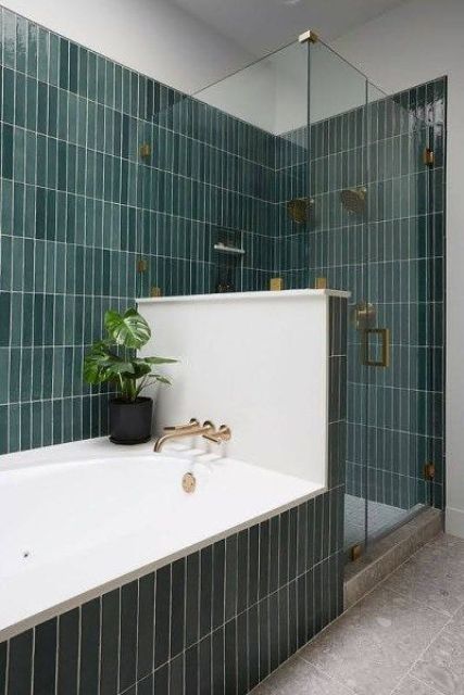 a lovely bathroom clad with green skinny tiles, with a half wall to divide the bathtub and shower space is amazing