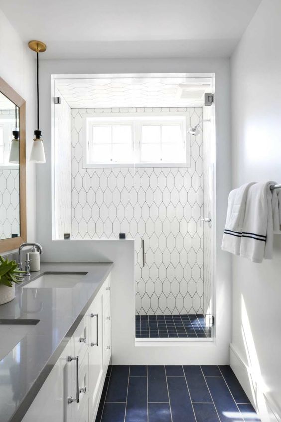 a modern coastal bathroom clad with navy and white tiles, a pony wall in the shower space and a white vanity