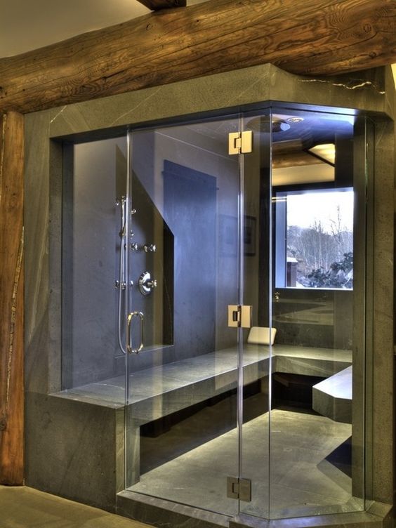 a modern steam room clad with grey stone, with a window and a long bench looks very edgy and bold