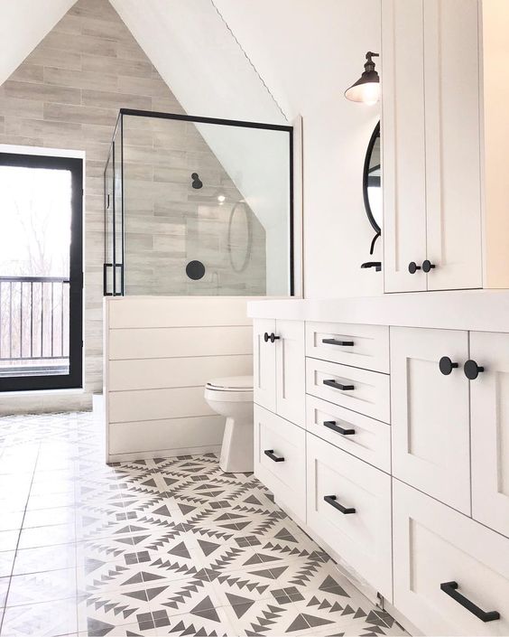 a neutral farmhouse bathroom with mosaic tiles, planked walls and cabinets, a shower space with a half wall