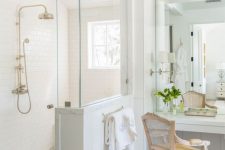 a neutral vintage bathroom with a shower space with a half wall, a vanity with a mirror and a vintage chair