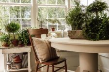 a neutral vintage sunroom with a stained chair, potted greenery and neutral textiles for a chic feel