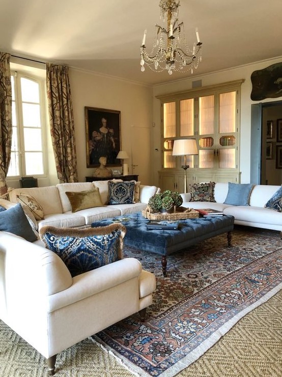 a refined and chic Provence living room with neutral furniture, a crystal chandelier, printed textiles and a beautiful artwork