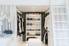 a refined and chic black and white space with a walk-in closet, a ladder and a loft sleeping space, sleek white furniture is amazing
