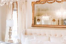 a refined neutral bedroom with a mirror in a chic frame, a crystal chandelier and a gorgeous upholstered bed