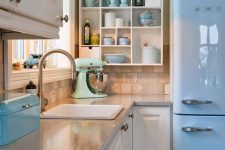 a retro kitchen with white shaker style cabinets, grey countertops, an open storage shelf, a blue fridge and blue and mint touches here and there