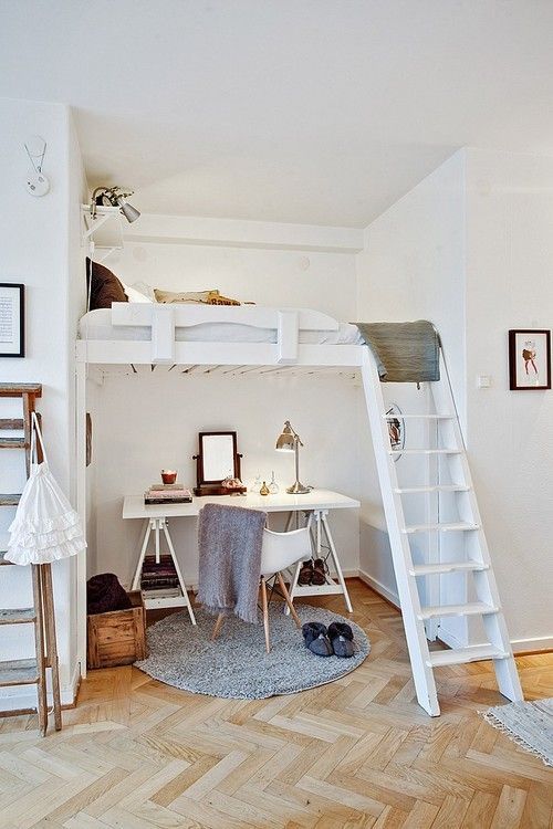 a small Scandi space with a trestle desk and a white chair, a loft bed with neutral bedding, a lamp and a shelf