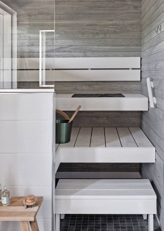 a small minimalist steam room clad with weathered wood and with whitewashed benches