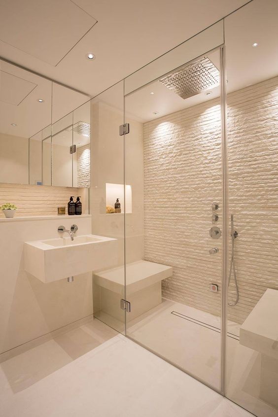 A small yet chic white steam room with a stone wall and mini benches plus built in lights is cool